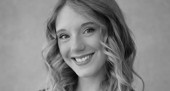 Smiling woman with wavy hair looking at the camera (black-and-white portrait).