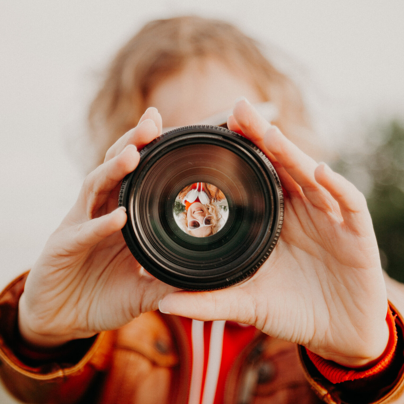 Young woman looking through camera lens. Photography and art concept.